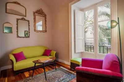 a living room with a green couch and pink chairs at Aurora Apartment by Domus Sicily in Palermo