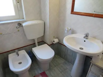 a bathroom with a white toilet and a sink at Awesome terrace and apartment in the city centre in Palermo