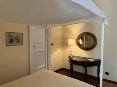 a bedroom with a canopy bed with a table and a mirror at La casa del Maestro in Palermo