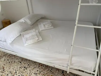 a white bed with two pillows and a ladder at Il Rifugio della Grotta S.Ninfa in Santa Ninfa