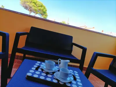 a table with cups and saucers on a balcony at Villemar in Isola delle Femmine