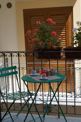 a green table and chairs on a balcony with flowers at Guascone Apartments in Palermo