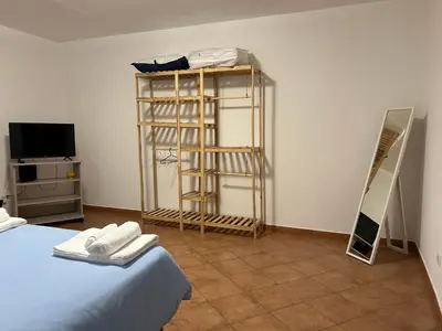 a room with a bed and a shelf and a television at DM house in Palermo