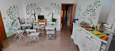 a kitchen with a table and chairs and trees on the wall at I Sollazzi in Palermo