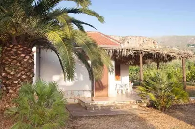 a house with a palm tree in front of it at sicilian rustic in Scopello