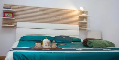 a bed with blue and green sheets and pillows at King's Residence in Balestrate