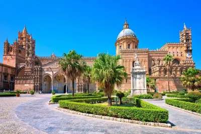 a large building with palm trees and a clock tower at A casa di Alex in Palermo