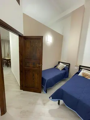 a bedroom with two beds and a wooden door at Civico 356 in Castellammare del Golfo