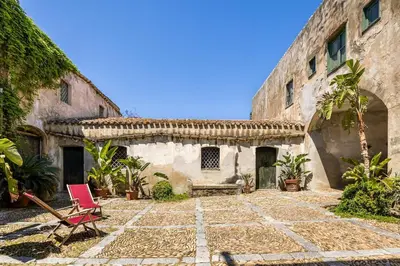 an old stone building with a chair in a courtyard at Villa surrounded by Nature overlooking the Sea - Cefalù in Lascari