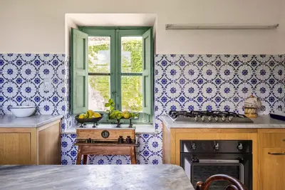 a kitchen with blue and white tiled walls and a window at Villa surrounded by Nature overlooking the Sea - Cefalù in Lascari