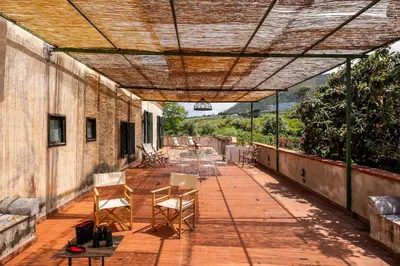 a patio with a table and chairs on it at Villa surrounded by Nature overlooking the Sea - Cefalù in Lascari