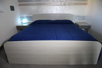 a bedroom with a large bed with blue sheets and two tables at Villa Letizia in Campofelice di Roccella