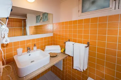 an orange tiled bathroom with a sink and a mirror at Veranda sul Porticciolo in Castellammare del Golfo