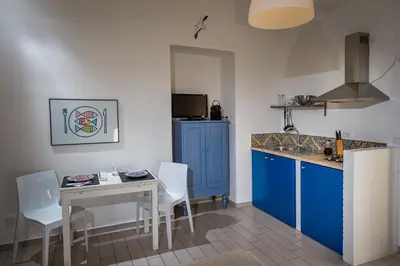 a kitchen with blue cabinets and a table with white chairs at Veranda sul Porticciolo in Castellammare del Golfo