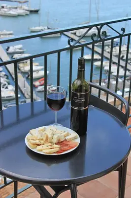 a table with a glass of wine and a plate of food at Veranda sul Porticciolo in Castellammare del Golfo