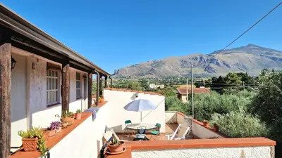 a balcony of a house with a table and an umbrella at Appartamenti Amagea in Scopello