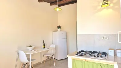 a kitchen with a white refrigerator and a table at Appartamenti Amagea in Scopello