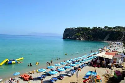 a beach with many umbrellas and people in the water at Appartamenti Amagea in Scopello