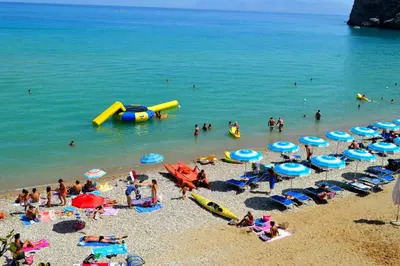 a group of people on a beach with umbrellas at Appartamenti Amagea in Scopello