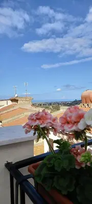a vase of flowers on a balcony with a view of the beach at Regina Stella in Lascari