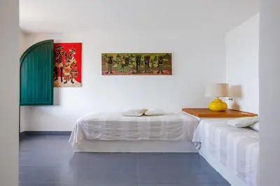 a white room with two beds and a table at Isulidda Gaia Mare in San Vito lo Capo
