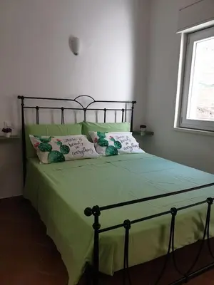 a bedroom with a bed with green sheets and pillows at Le Due Perle in Palermo