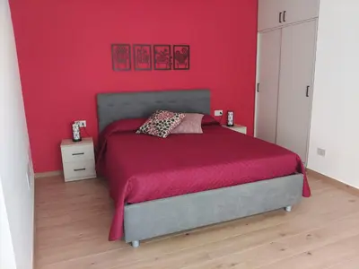a bedroom with a bed with a red wall at La Nicaredda in Alcamo
