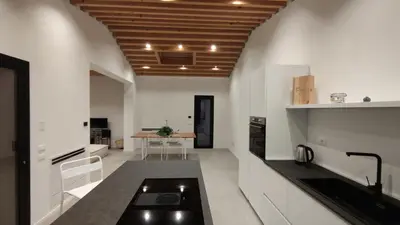 a kitchen with white walls and a wooden ceiling at Casa di Pino in Cefalù