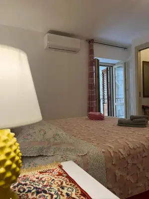 a bedroom with a bed with a lamp and a window at Casetta di Ale al Capo in Palermo