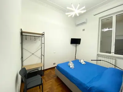 a bedroom with a blue bed and a chair at Kamaffari Central Apartment in Palermo