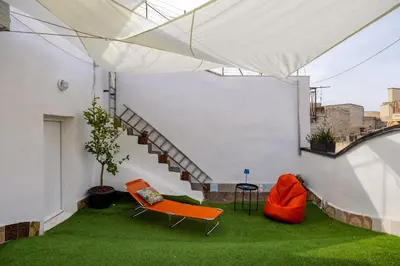 a living area with orange chairs and a staircase at Madre Terra Airport Apartment & Rooms in Terrasini