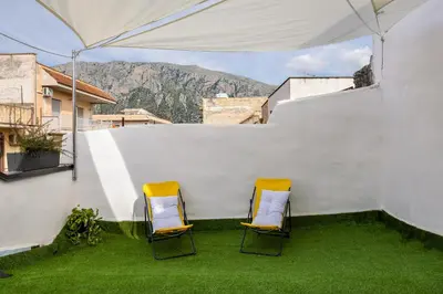 two chairs sitting on a patio with a white wall at Madre Terra Airport Apartment & Rooms in Terrasini