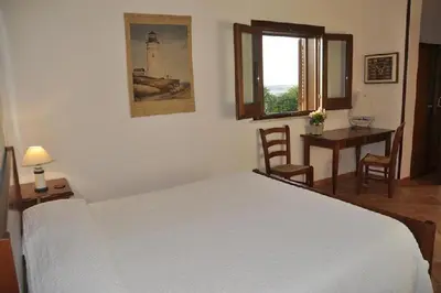 a bedroom with a white bed and a desk and a window at Punto de Vista B&B Makari in San Vito lo Capo