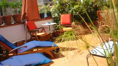 a patio with chairs and an umbrella and plants at Alle Terrazze del Borgo Vecchio in Palermo