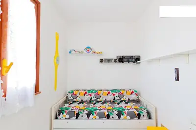 a white room with a crib with colorful pillows at Villa Verdemare in San Vito lo Capo