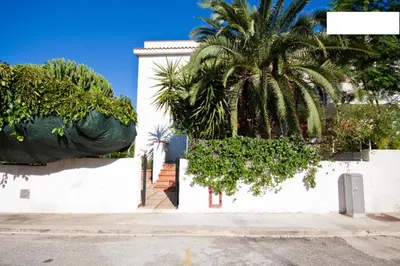 a white building with a palm tree in front of it at Villa Verdemare in San Vito lo Capo