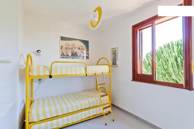 a yellow bunk bed in a room with a window at Villa Verdemare in San Vito lo Capo