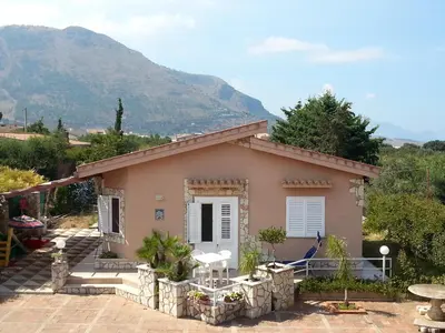 a small house with a mountain in the background at Villa Oasi del Relax Flavianna in Castellammare del Golfo