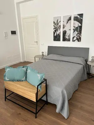 a bedroom with a bed and a bench with pillows at SPRING APARTMENTS in Palermo