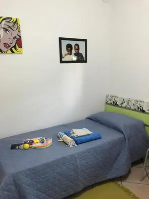 a bed with a blue comforter and two pictures on the wall at Casa al mare a Campofelice di Roccella - Cefalù in Lascari