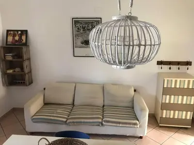 a living room with a couch and a bird cage at Casa al mare a Campofelice di Roccella - Cefalù in Lascari