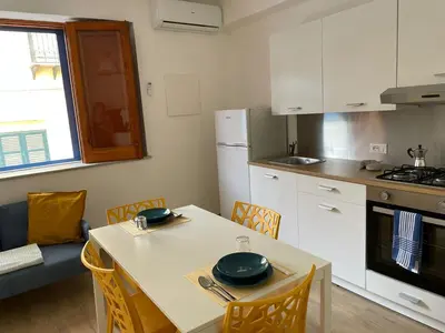 a kitchen with a white table and chairs and a kitchen with a stove at Casa di Leda in Santa Flavia