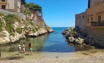 a group of people standing in the water on a beach at Casa di Leda 1 in Santa Flavia