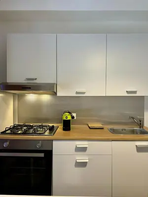 a kitchen with white cabinets and a stove and a sink at Casa di Leda 1 in Santa Flavia