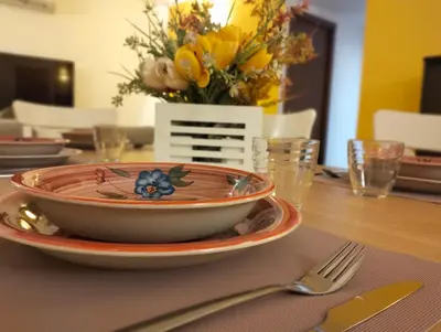 a plate on a table with a vase of flowers at Alvarado - Your Home in Sicily in Carini