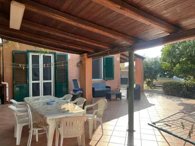 a patio with a table and chairs under a wooden pergola at Villacinisi in Cinisi