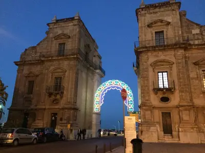 two old buildings with a carnival arch between them at Casa degli Allori in Palermo