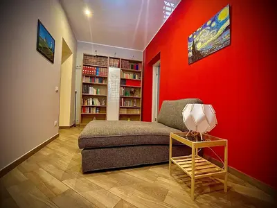 a living room with a couch and a red wall at Casa Batù alle porte del Capo in Palermo