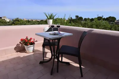 a table with two glasses of wine on a balcony at Miss Sicily B&B in Terrasini