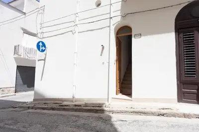 a white building with a door on a street at GuestHost - Castellammare Stella Apartments in Castellammare del Golfo